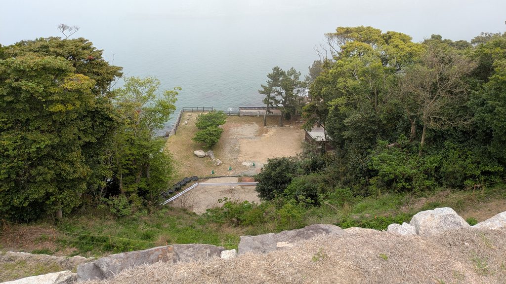 唐津城本丸から木々と眼下の平地越しに望む唐津湾